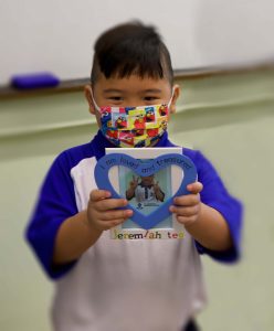 A student holding out a photo frame handicraft he made.