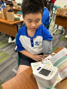 Student taking his blood pressure using a blood pressure monitor.